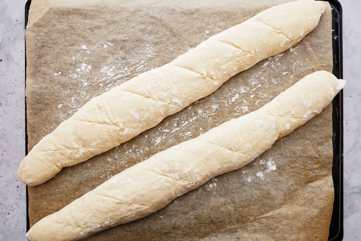 Unbaked bread dough with scores cut on top.