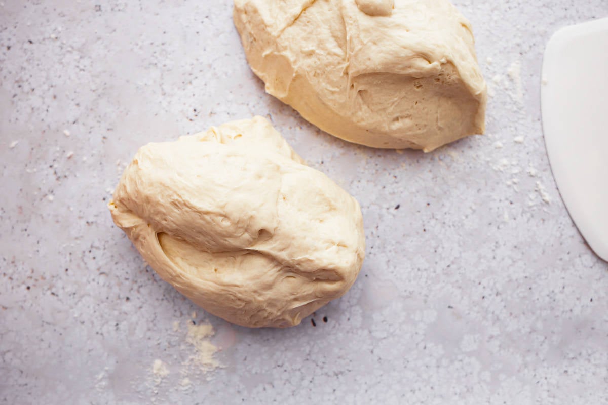 Two balls of baguette dough on a floured surface.