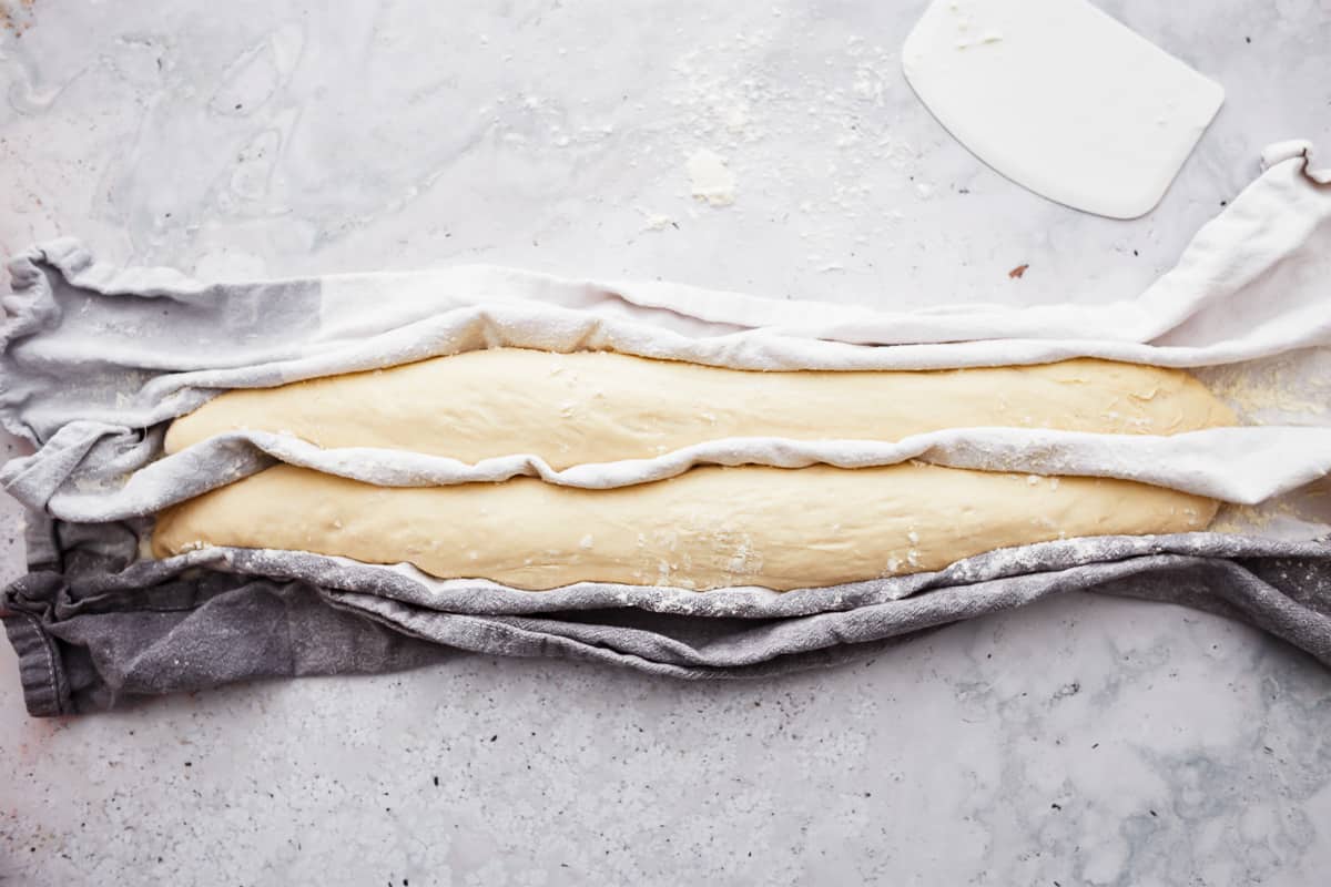 Baguette dough between folded kitchen towels.