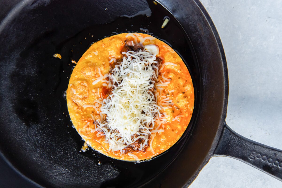 tortilla with meat and cheese in a skillet