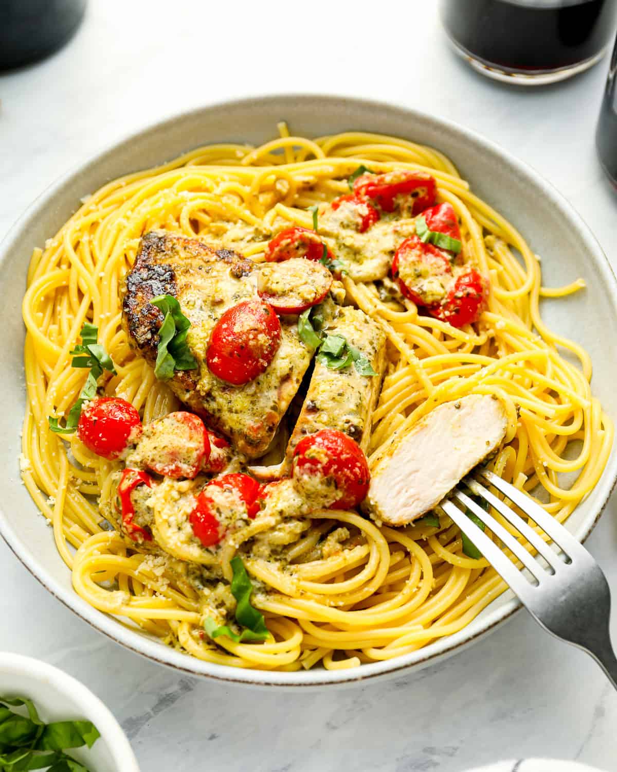 a serving of pesto chicken over spaghetti with a fork.