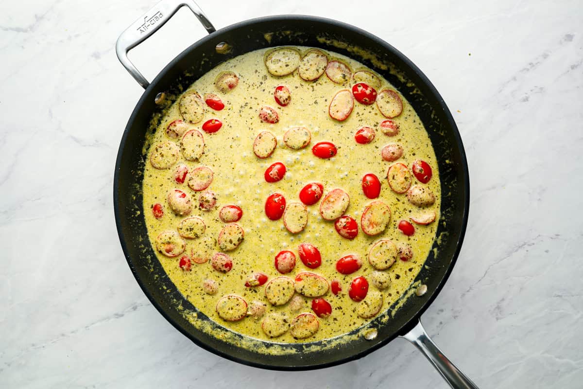 creamy pesto sauce and tomatoes in a skillet.